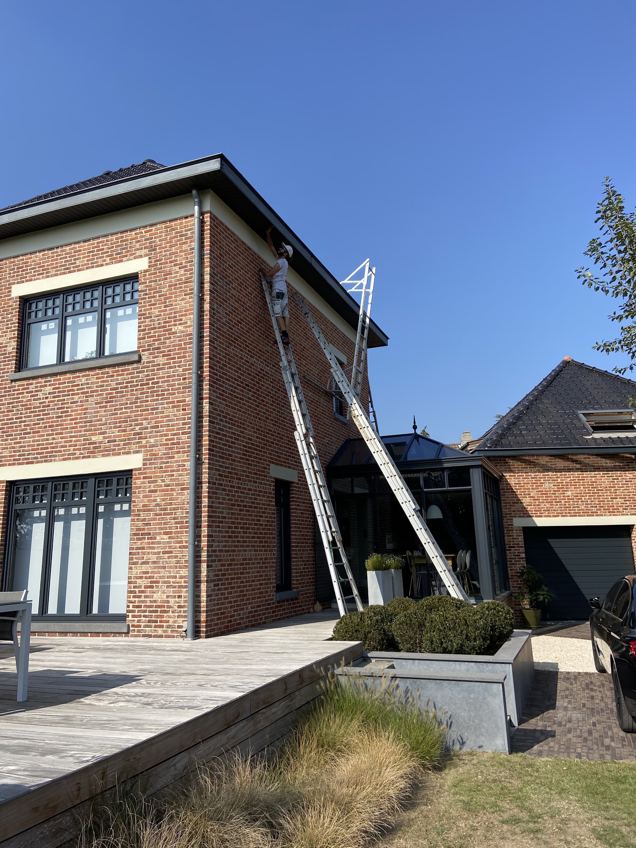 Schilder op ladder werkt aan de dakrand van een woning